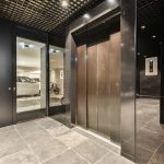 the inside of a building with two doors and one door opened to reveal a car parked in the parking lot